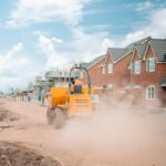 a large yellow truck driving down a dirt road
