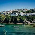 white and green boat on water near white concrete building during daytime