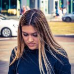 a woman standing on the street looking at her cell phone