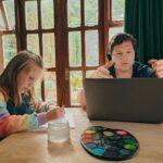 a woman and a girl sitting at a table with a laptop