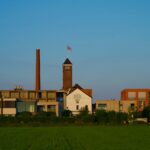 a building with a clock tower in the middle of a field
