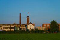 a building with a clock tower in the middle of a field