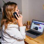 a woman sitting at a desk with a laptop and a phone