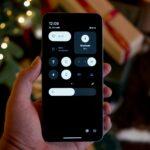 Hand holding a smartphone with a dark interface.