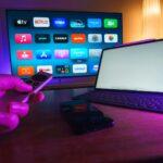 A person holding a remote control in front of a TV