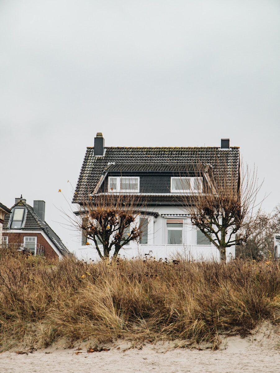 a house on the beach next to some trees