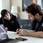 a man and a woman sitting at a table with a laptop