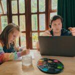 a woman and a girl sitting at a table with a laptop