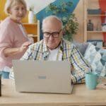 Elderly couple using a laptop in a living room.