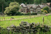 Stone wall in foreground with rural house behind