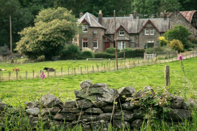 Stone wall in foreground with rural house behind