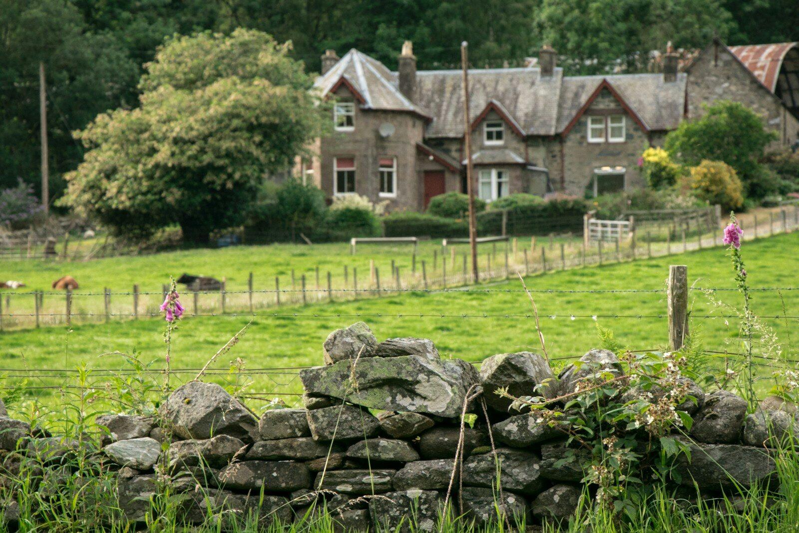 Stone wall in foreground with rural house behind